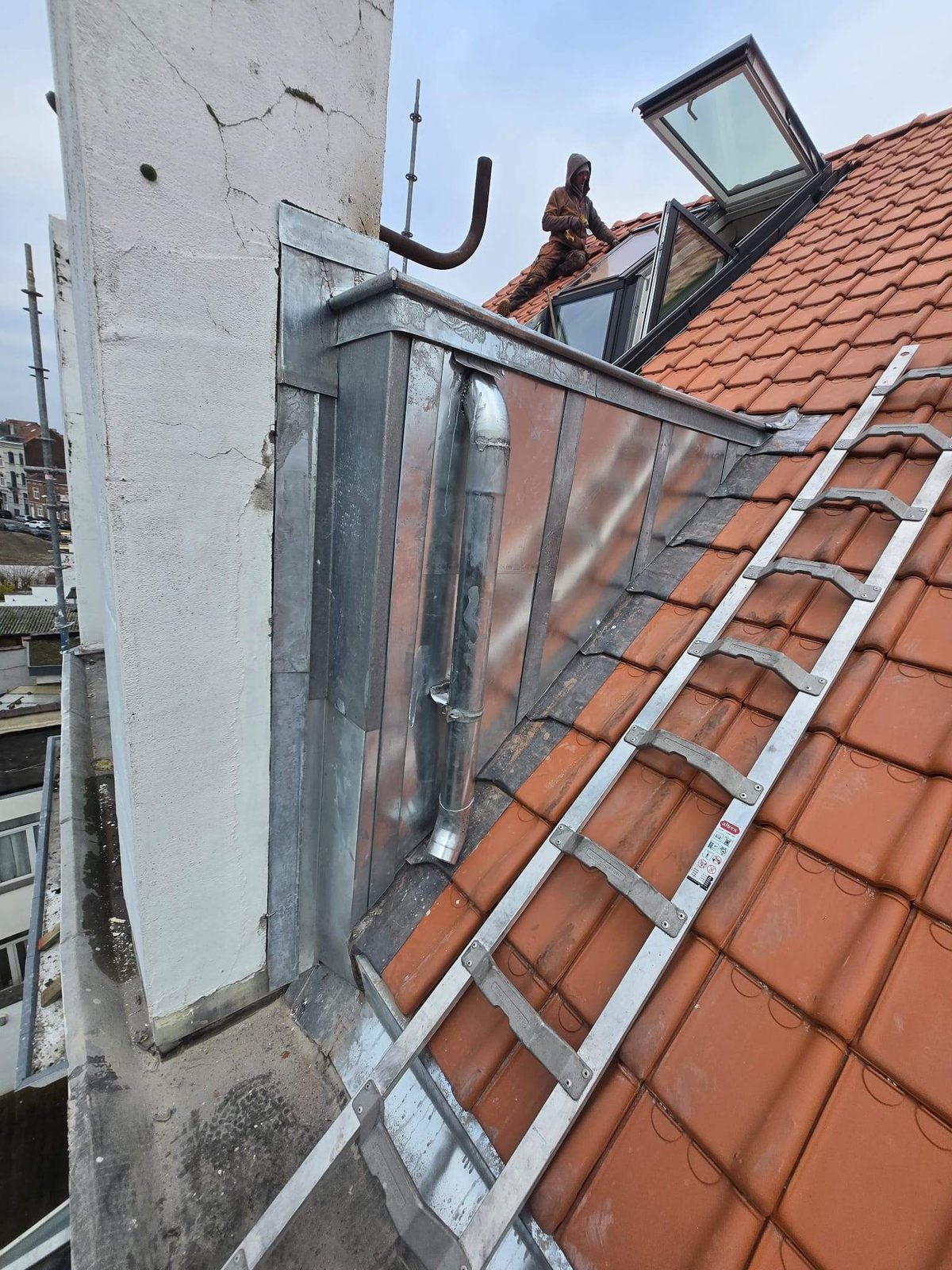 Zinc flashing around a chimney on a tiled roof